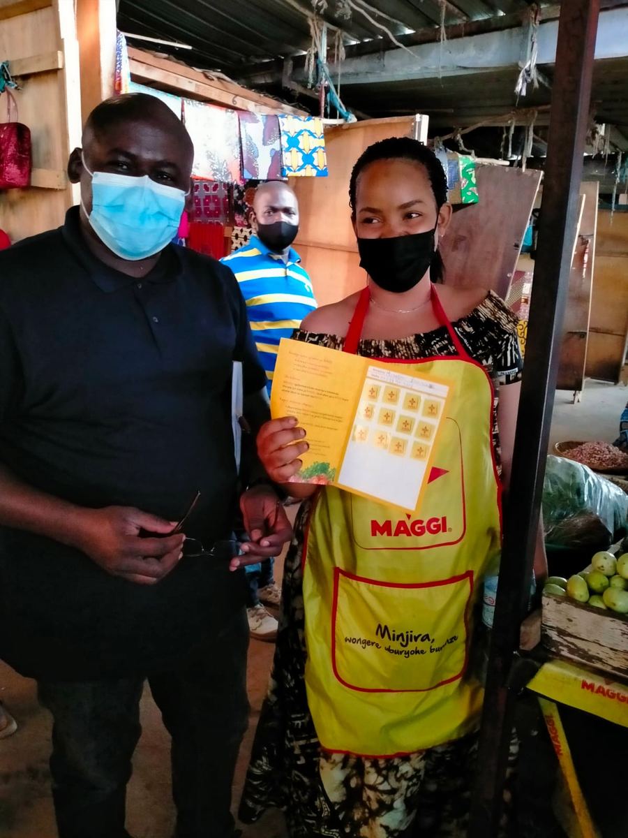 A market vendor in a MAGGI apron shows her loyalty programme stamp card