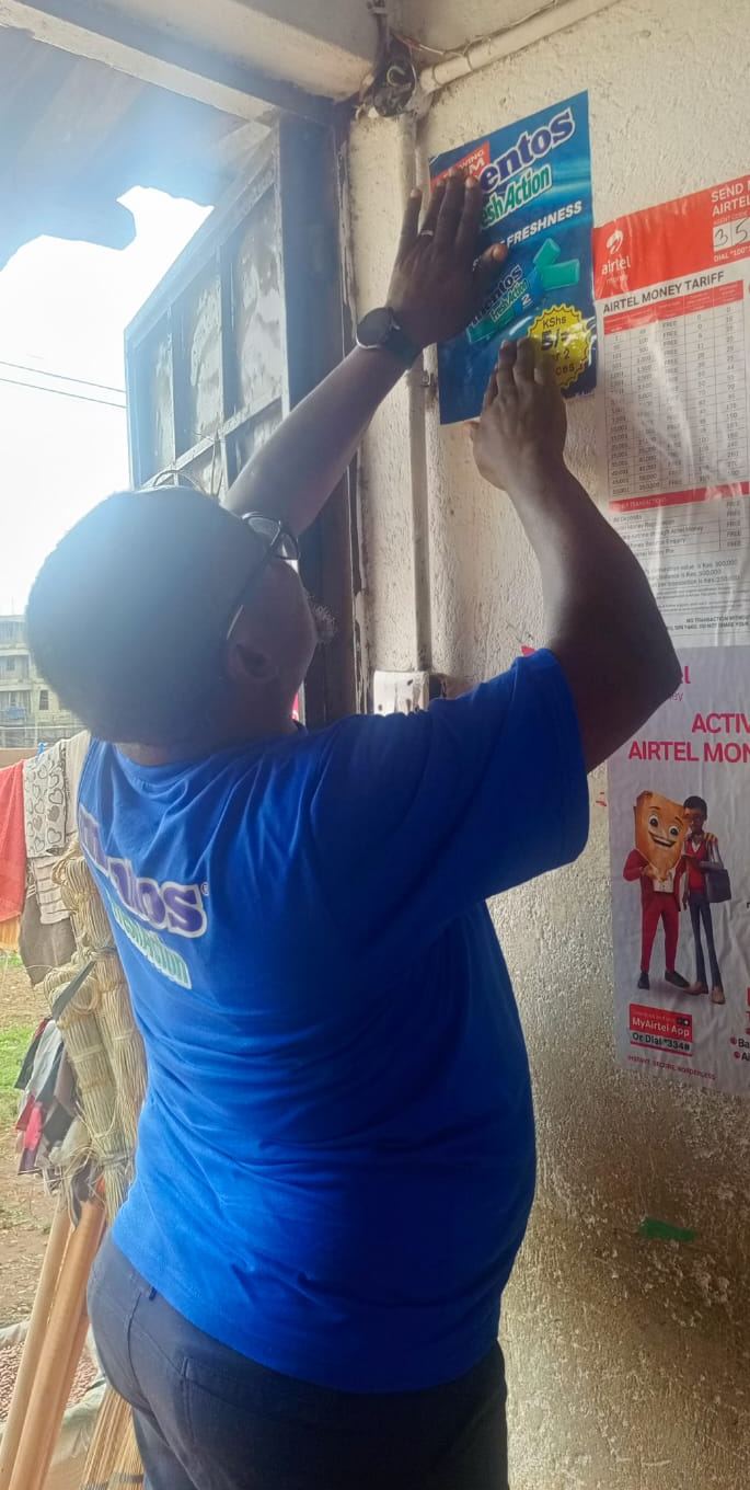 Putting up a MENTOS point-of-sale poster at a retail outlet